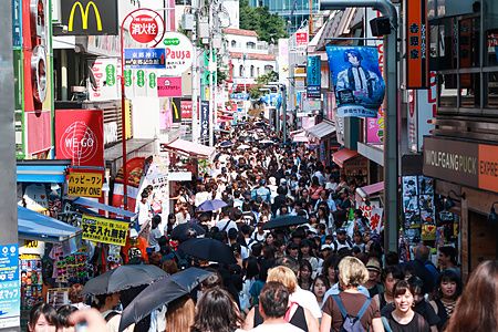 Strada affollata di Takeshita Dori a Tokyo con negozi e insegne colorate.