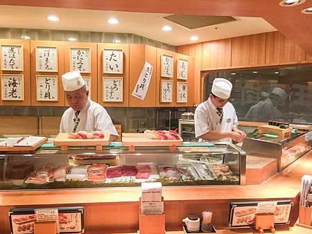 Due chef in uniforme preparano sushi dietro al bancone nel locale Tama Sushi a Tachikawa, Tokyo.