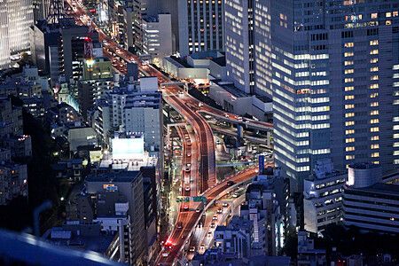 Vista notturna di Tokyo con strade trafficate e grattacieli illuminati.