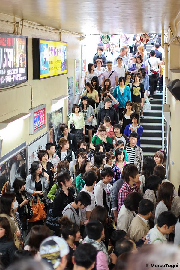 Numerose persone camminano lungo una scala all'interno di un passaggio pubblico nella folla Harajuku Tokyo, in Giappone.