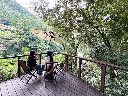 Due persone sedute in un'area relax vicina al ristorante a Kurochaya, su una terrazza in legno circondata dalla foresta.