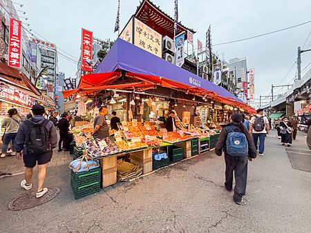 Veduta di una bancarella di frutta nel mercato di Ameyoko a Ueno, con diverse persone che camminano lungo la via.