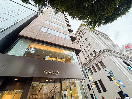 Facciata esterna del Wako Tea Salon a Ginza con vetrate e insegna dorata sotto alberi frondosi.