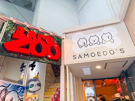 L'ingresso a Samoedos con un'insegna che ritrae tre cani stilizzati accanto all'insegna rossa di un altro negozio.