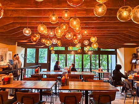 Interno del ristorante Smokehouse con tavoli in legno e lampade a sfera sospese in una strada tra Harajuku e Shibuya.
