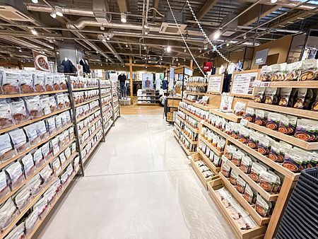 Corridoi del negozio Muji, a Tokyo, con scaffalature in legno piene di confezioni di curry e una persona sullo sfondo.