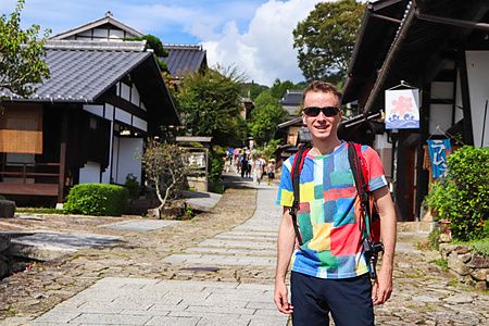 persona con maglietta colorata e zaino su strada acciottolata a Magome
