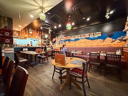 Veduta degli interni del ristorante Seven Hills ad Osaka con tavoli, decorazioni a tema desertico e persone presenti.