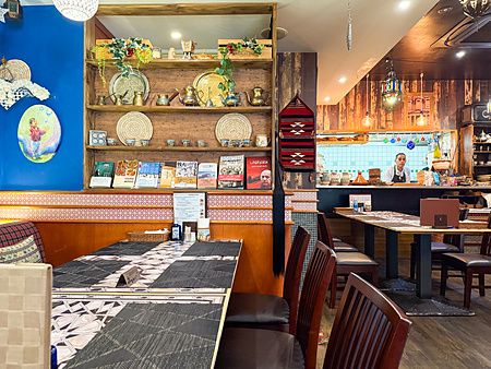 Veduta degli interni del ristorante arabo Seven Hills a Osaka, con scaffali decorativi, tavoli e un individuo al bancone.