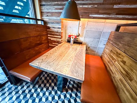 L'interno del ristorante Smokehouse a Tokyo con un tavolo in legno, panche color cuoio e pavimento a motivi geometrici.