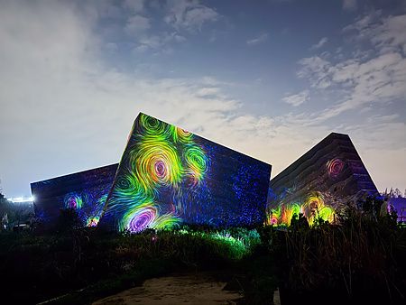 Installazione di luci colorate con vortici su strutture architettoniche nel teamLab Botanical Garden Osaka.