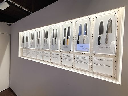 Esposizione di coltelli giapponesi con didascalie tecniche presso Tojiro Knife Gallery a Sennichimae Doguyasuji, Osaka.