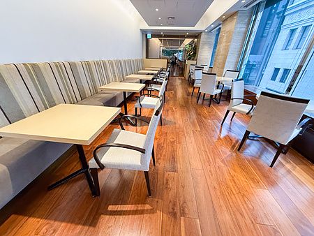 L'interno a Wako Tea Salon presenta tavoli e sedie disposti in fila lungo una vetrata che affaccia su Ginza.