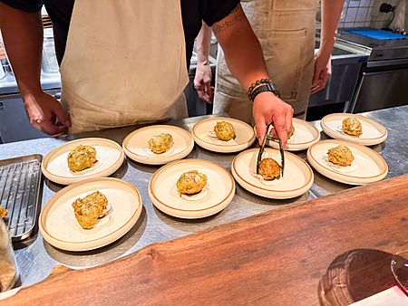 Impiattamento delle zeppoline con funghi a Mushroom Tokyo con chef al lavoro su un bancone in acciaio.
