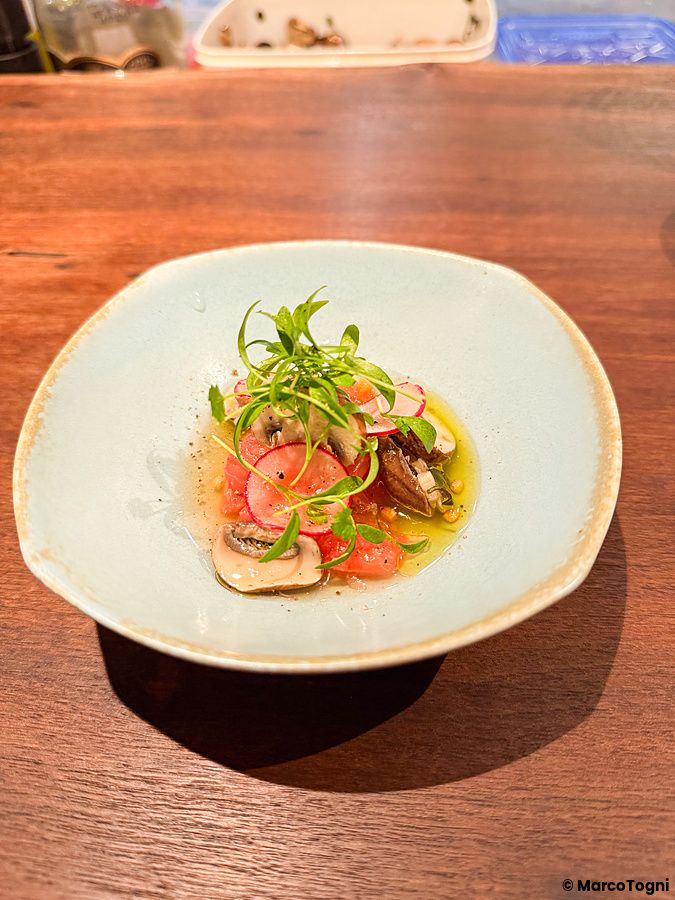 Un piatto di aguachile con funghi, specialità vegana servita in una ciotola su un tavolo di legno al Mushroom Tokyo.