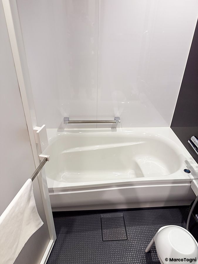 Bagno in stanza a JR East Hotel Mets Premier Akihabara con vasca bianca e pavimento scuro.