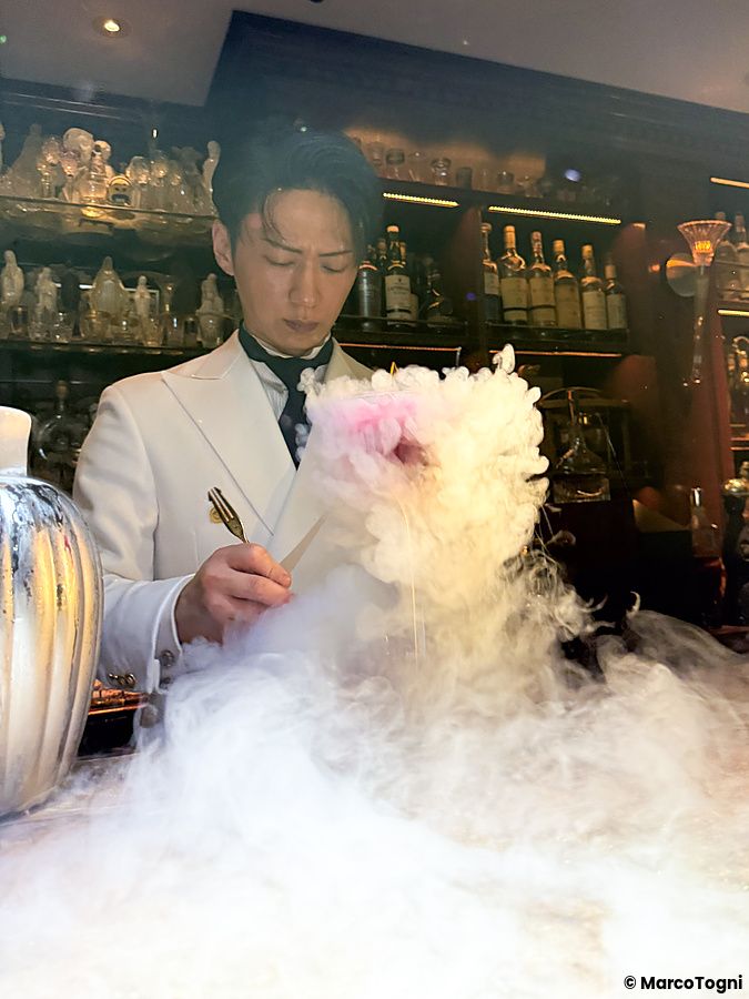 Un barista in divisa bianca prepara un cocktail fumante dietro il bancone del Bar Centifolia a Tokyo.