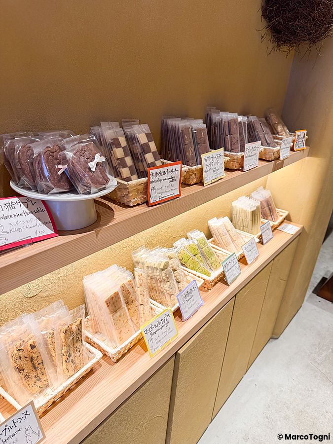 Ripiani in legno all'interno di Naki vegan sweets a Namba, Osaka, con biscotti vegani confezionati in cesti.