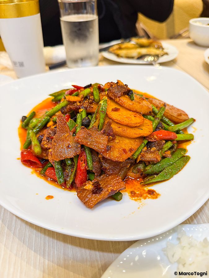 Un piatto di carne e verdure a Mara Daigaku a Ueno, con carne, fagiolini, patate e peperoncini rossi su un tavolo.