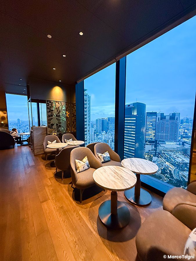 Interni della club lounge a Centara Grand Hotel Osaka con poltrone, tavolini e grandi vetrate affacciate sulla città.