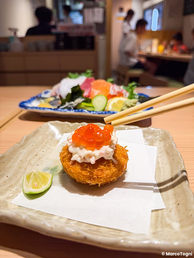 Una crocchetta guarnita con uova di salmone su un piatto nel Ristorante New Sushi Center Harukiya a Osaka.