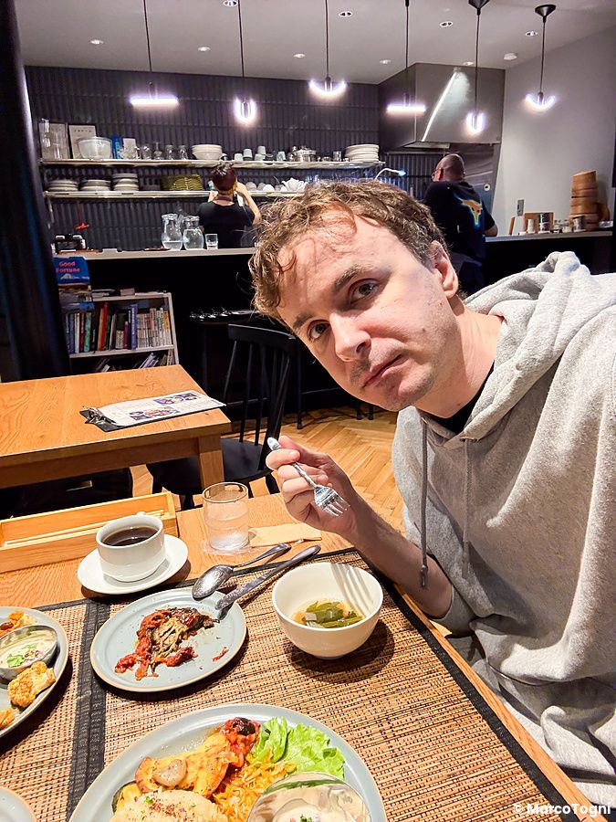 Marco Togni seduto al tavolo del ristorante vegano VeganLife SoiSoi a Kyoto mentre mangia piatti a base vegetale.