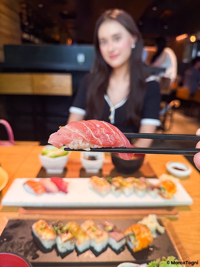 Un nigiri al tonno tenuto con le bacchette presso il ristorante Kinka Sushi Bar Izakaya nel quartiere di Shibuya.