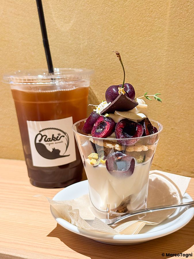 Un dessert con ciliegie in un bicchiere trasparente e una bevanda fredda presso Naki vegan sweets a Namba, Osaka.