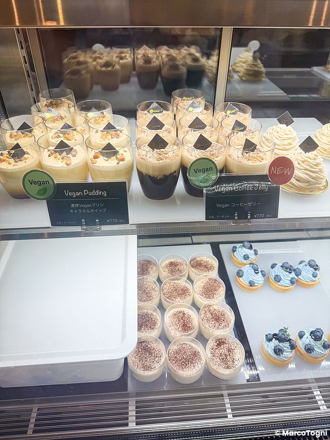 Una vetrina refrigerata con vari tipi di dolci vegani e dessert esposti presso il ristorante Green Italian Torcia.