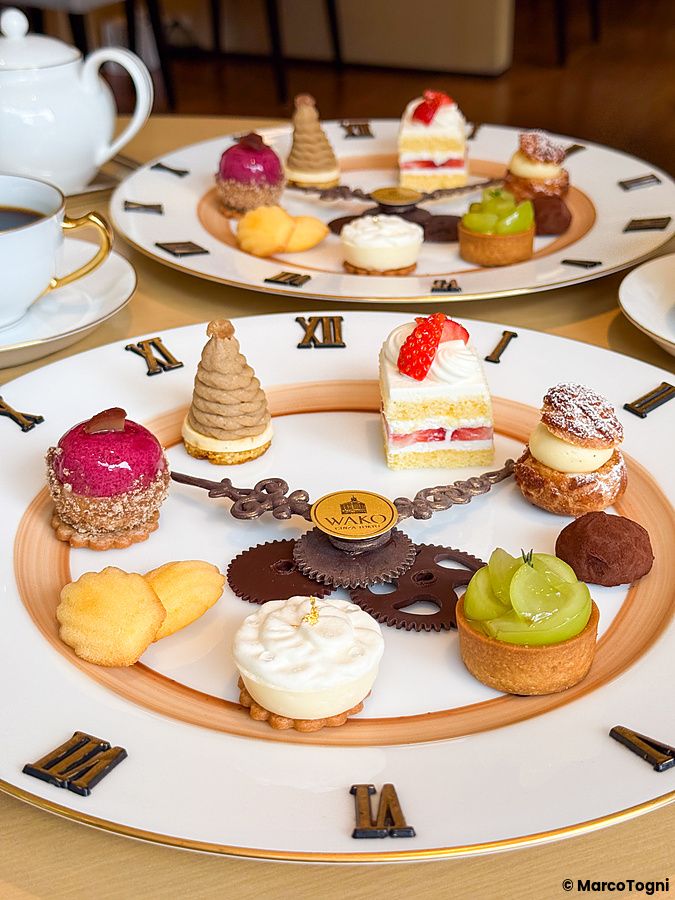 Una selezione di dolci su piatto a forma di orologio a Wako Tea Salon con pasticcini disposti come segnatempo.