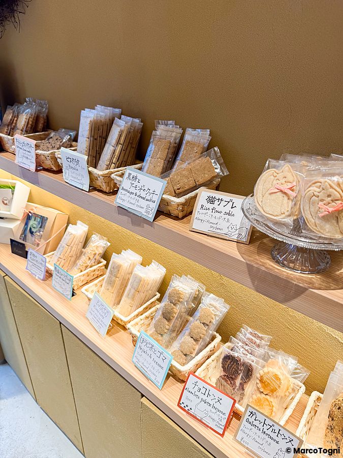 Scaffali in legno di Naki vegan sweets a Namba con vari pacchetti di dolci vegani esposti con cartellini descrittivi.