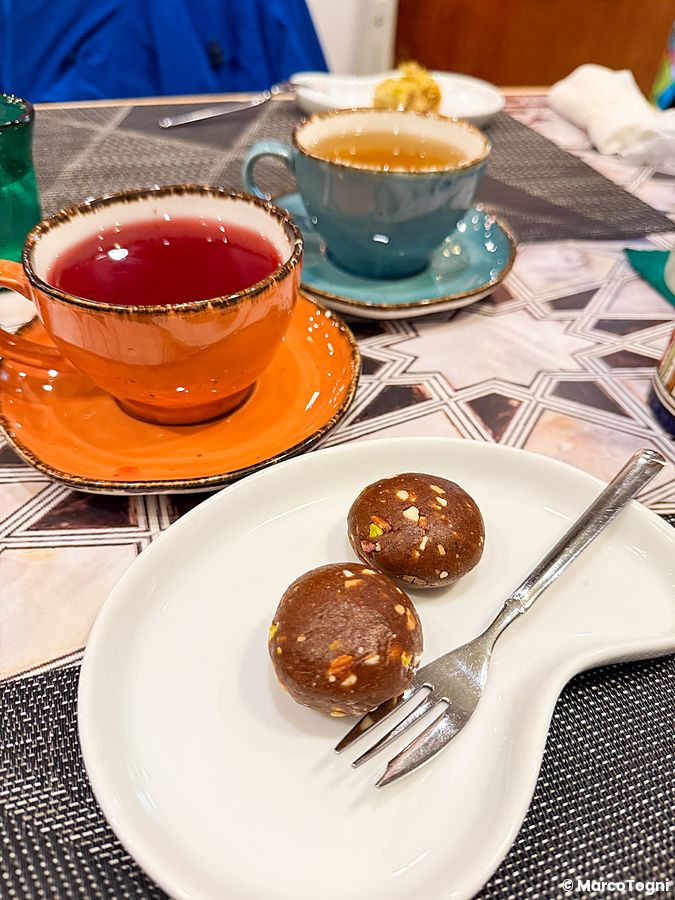 Due dolci vegani su un piattino bianco accanto a due tazze di tè in un ristorante.