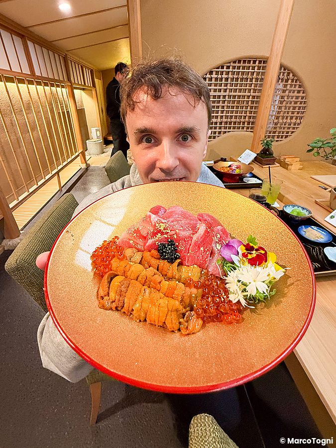Marco Togni tiene in mano un donburi premium con riccio di mare, otoro, chutoro e ikura all'interno del ristorante Waunn.