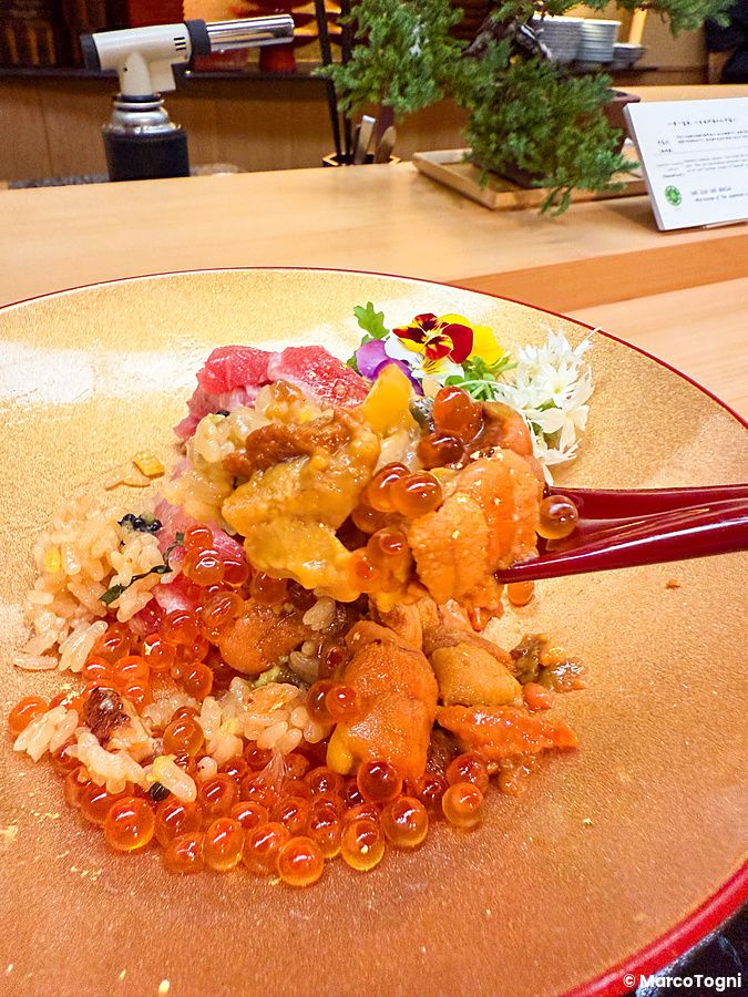 Un donburi premium con riccio di mare, otoro, chutoro e ikura servito su un piatto dorato presso il ristorante Waunn.