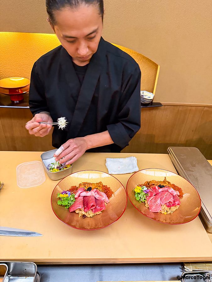 Uno chef prepara un donburi premium con riccio di mare, otoro, chutoro e ikura presso il ristorante Waunn ad Asakusa.
