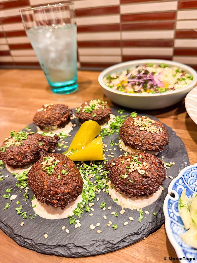 Falafel con semi di sesamo e cetrioli sott'aceto su un piatto di ardesia al ristorante Telaviv a Kyoto.