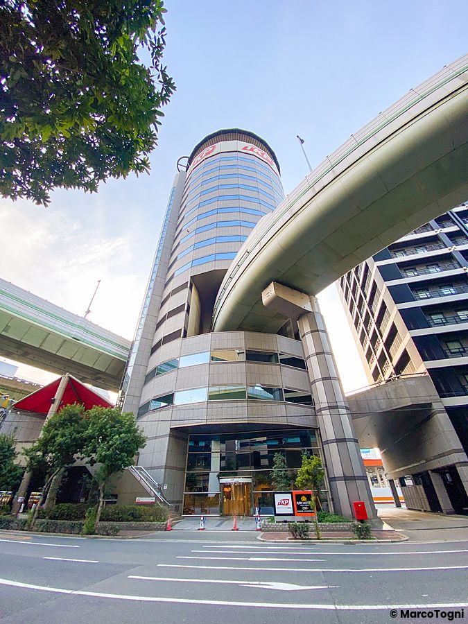 Veduta dal basso del Gate Tower Building ad Osaka con un'autostrada che attraversa la struttura dell'edificio.