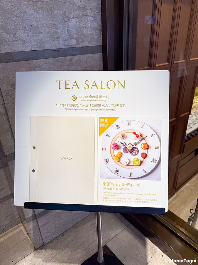 Una vetrina con menu a Wako Tea Salon a Ginza che mostra le regole del locale e un piatto di dolci.