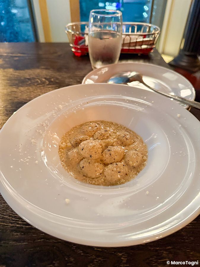 Un piatto di gnocchi con salsa cremosa servito sul tavolo di legno scuro del ristorante Cafe Legato a Shibuya.
