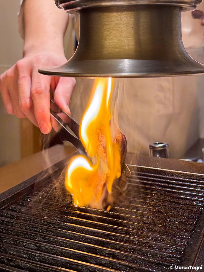 Una persona sta grigliando il tonno a Yakiuo Ishikawa in un ristorante di Roppongi a Tokyo.