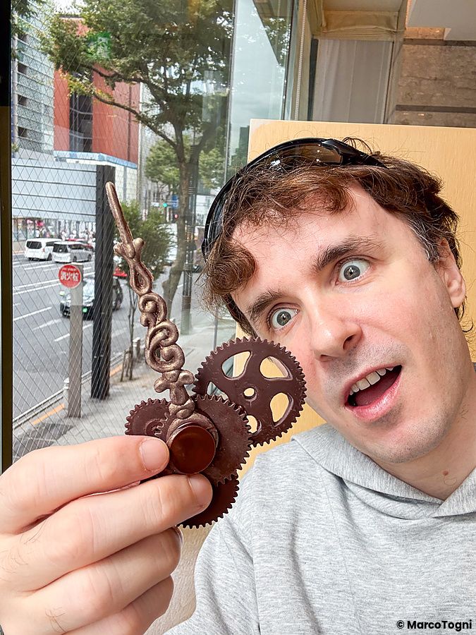 Marco Togni mostra ingranaggi di cioccolato da mangiare presso il Wako Tea Salon a Ginza, con una strada visibile oltre la...