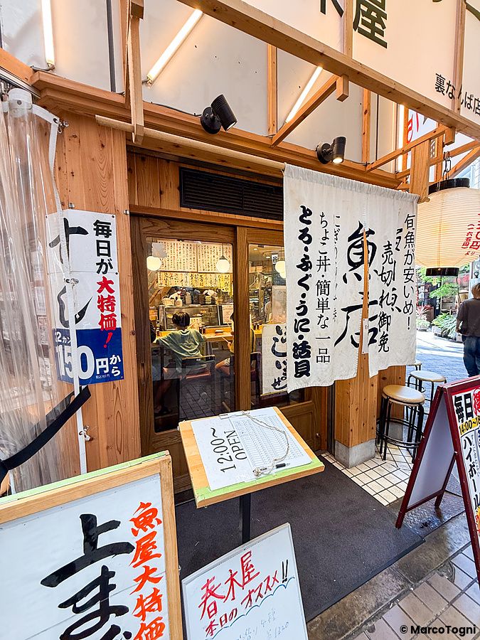L'ingresso in legno del Ristorante New Sushi Center Harukiya a Osaka con noren bianchi e menu esposto all'esterno.