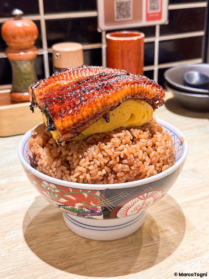 Una ciotola di riso sormontata da una frittata arrotolata e un filetto di unagi nel ristorante Izumo a Osaka.