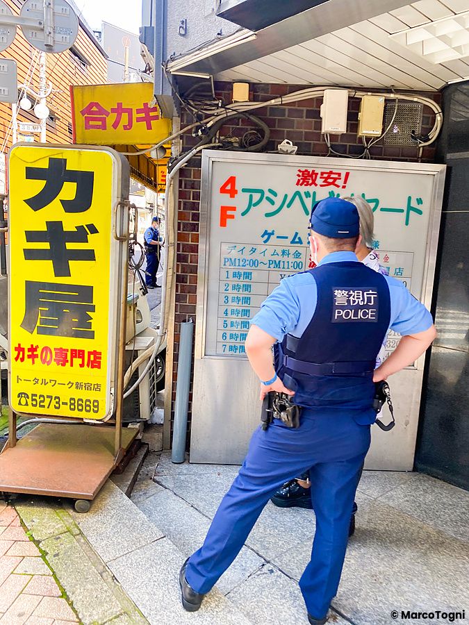 Un ufficiale di polizia controlla un edificio in una strada urbana giapponese.