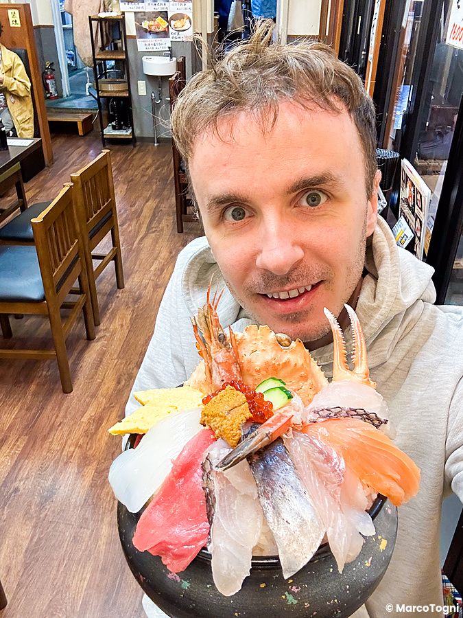 Marco Togni mostra una ciotola di donburi con vari tipi di pesce crudo all'interno del ristorante Kaisendon Ichiba.