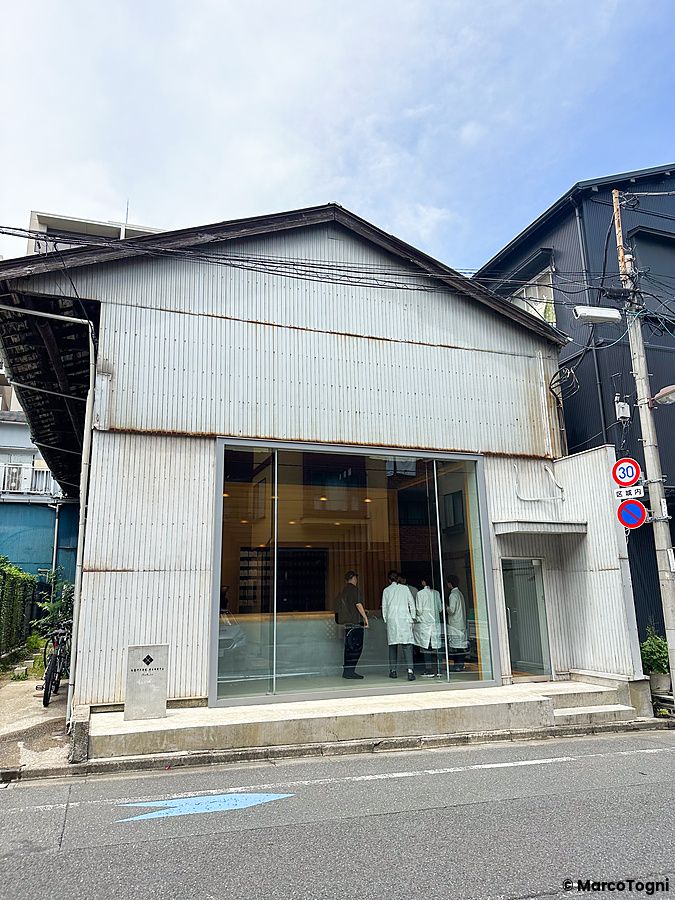 L'esterno del Koffee Mameya Kakeru a Tokyo con la sua caratteristica facciata in metallo ondulato e ampia vetrata.