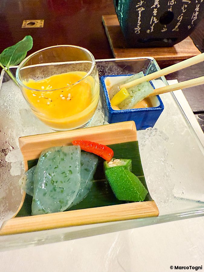 Un piatto di konnyaku a Kurochaya servito su ghiaccio con okra e una salsa gialla in un ristorante di Akiruno.