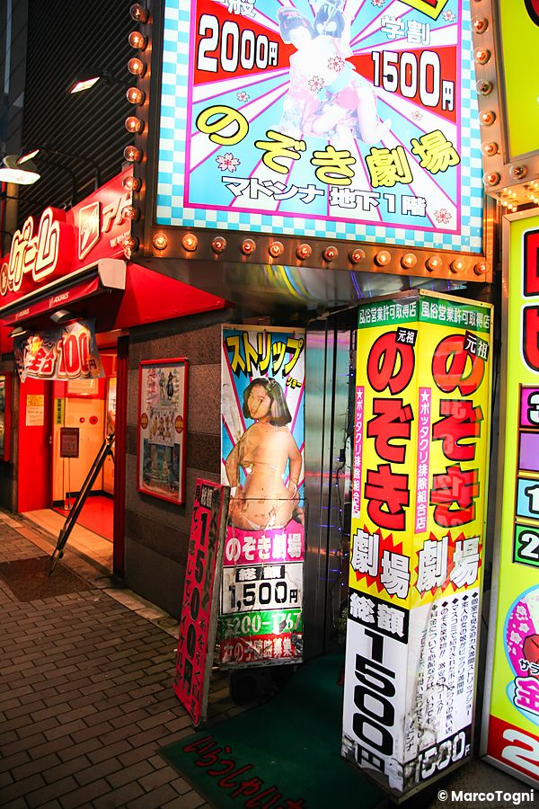 Ingresso di un locale di spogliarelli illuminato da cartelloni pubblicitari a Tokyo.