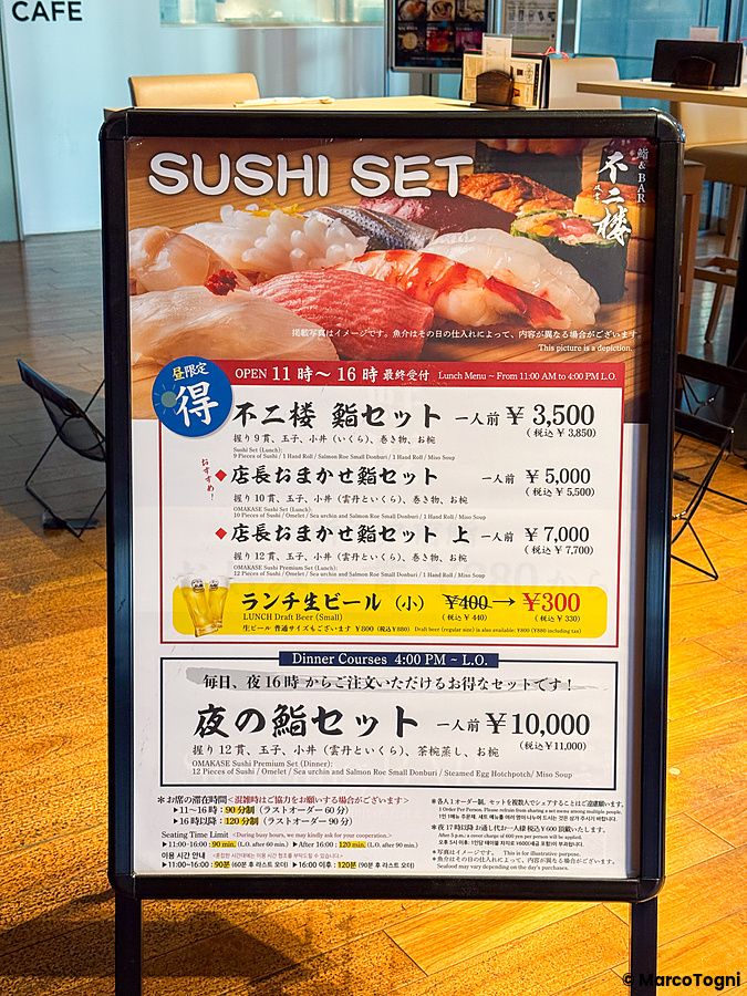 Una locandina col menu a Sushi & Bar Fujiro Marunouchi Tokyo con l'elenco dei set di sushi disponibili.