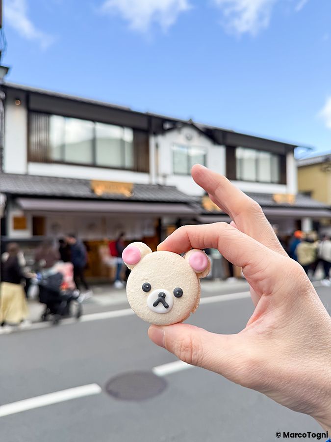 Un macaron a forma di Rilakkuma tenuto in mano davanti alla Rilakkuma Tea House ad Arashiyama.